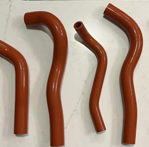 Flexible orange silicone hoses for automotive performance and customization, designed for fuel or coolant systems, showcasing high-quality materials and precision manufacturing.