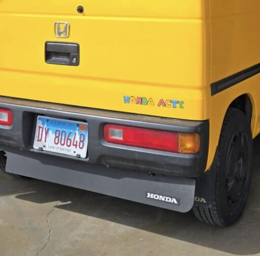 Colorful Honda Acty mini truck with custom decals, parked indoors, showcasing compact utility vehicle design and vibrant branding.