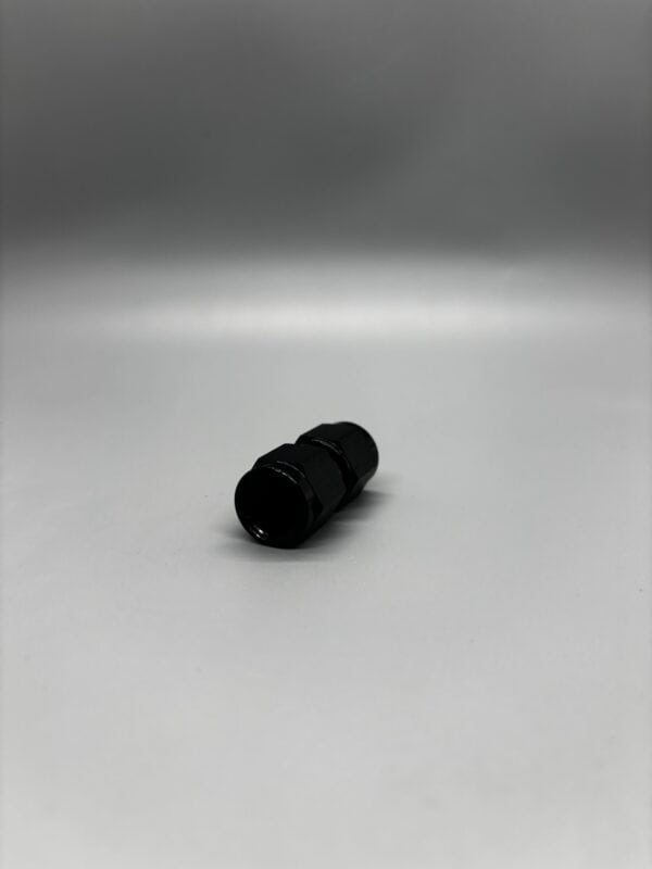 Close-up of a 6 AN female to female adapter used in automotive performance applications, showcasing its black anodized finish and precise threading.