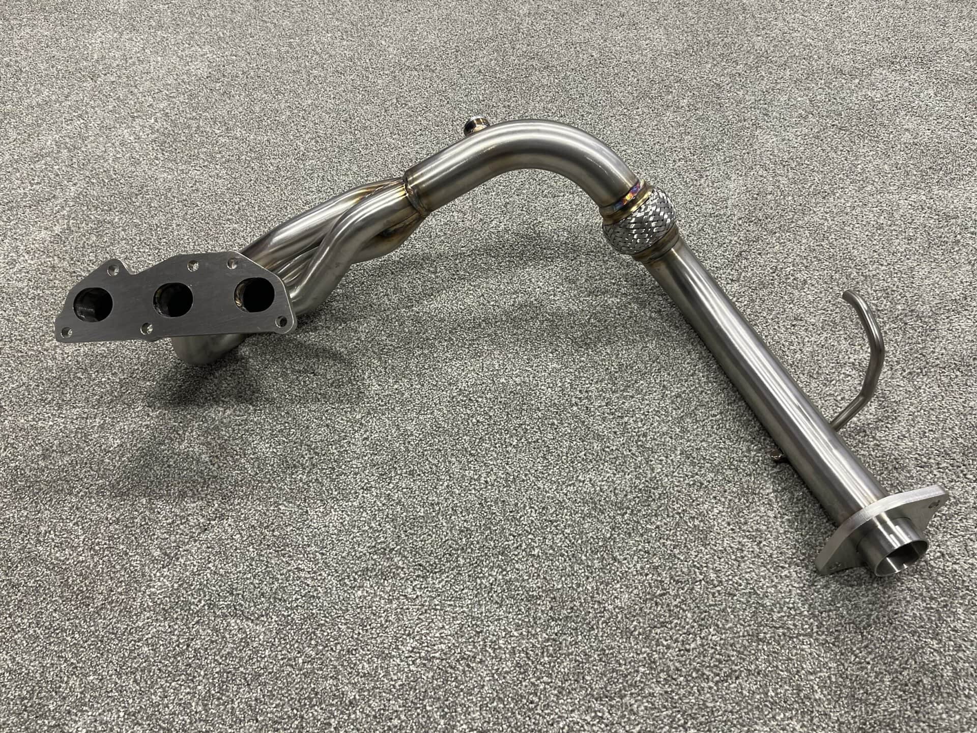 High-performance Acty exhaust header HA-3/4 made of stainless steel, designed for optimal exhaust flow and engine efficiency.